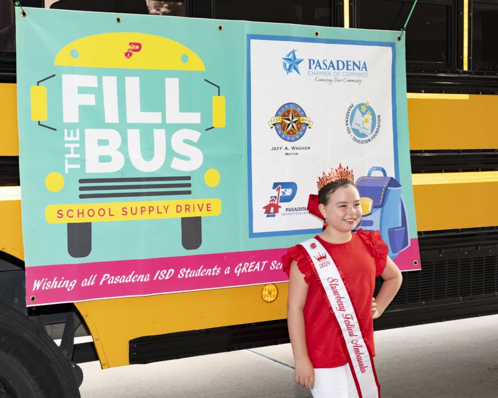 A young girl poses in front of the Fill the Bus school bus.