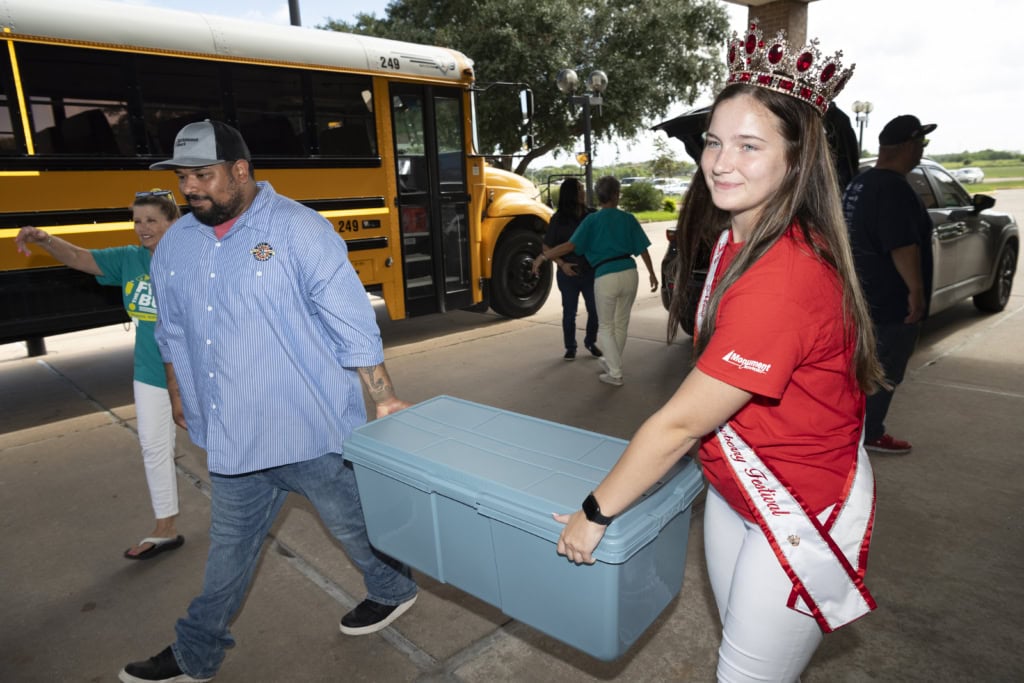 A teenage girl and a man carry school supplies for Pasadena's Fill the Bus drive.