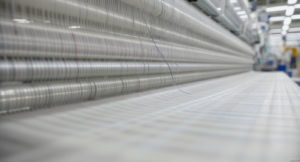 During warp sizing, an industrial loom spins synthetic yarns at high speed.